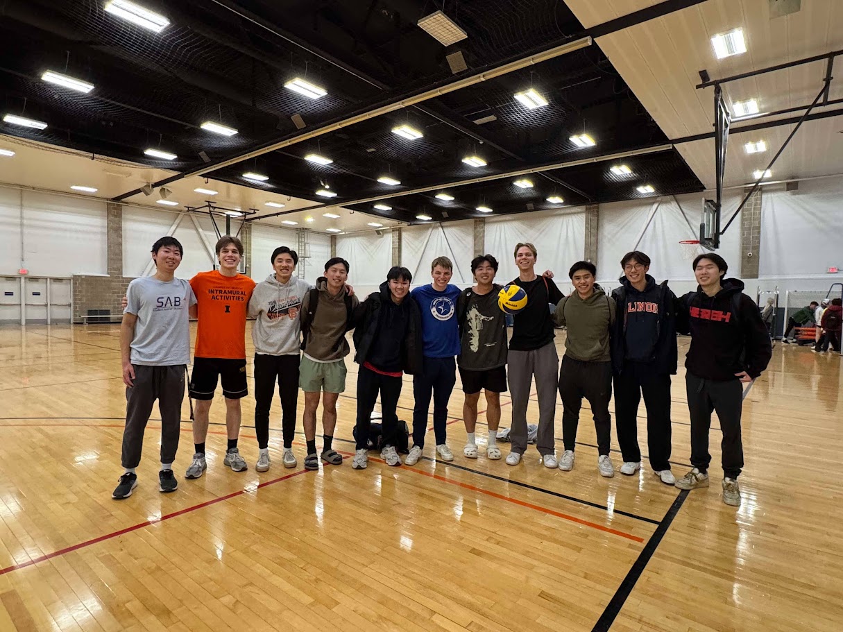 Anthony and friends posing with a volleyball in an indoor gym.